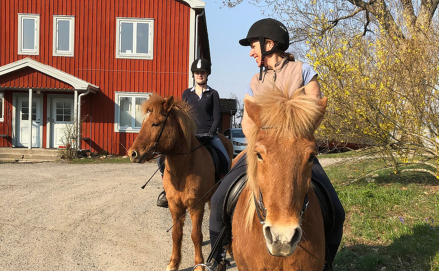 Häst lärare med en elev och internatet på bakgrund